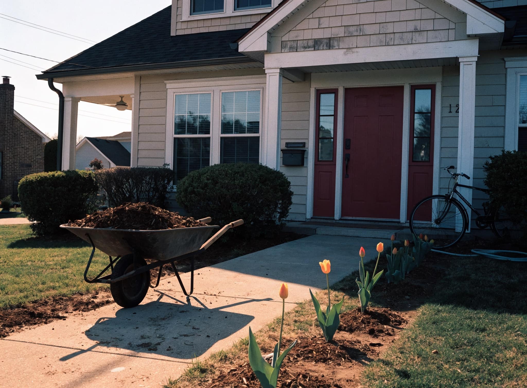 A charming pale blue starter home with a covered porch and a bicycle by the steps