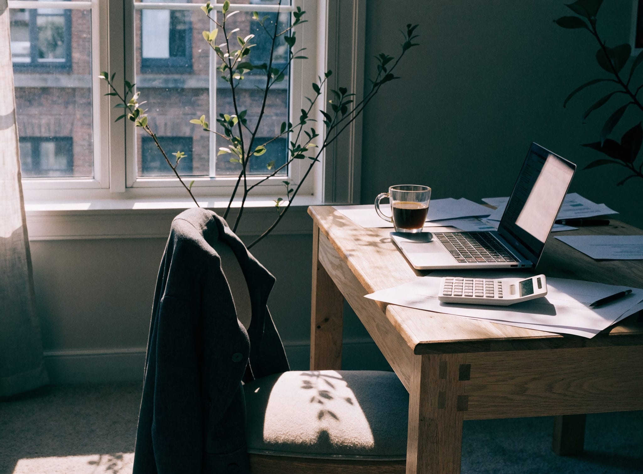Calm home office with a pale oak desk by a window in soft morning light