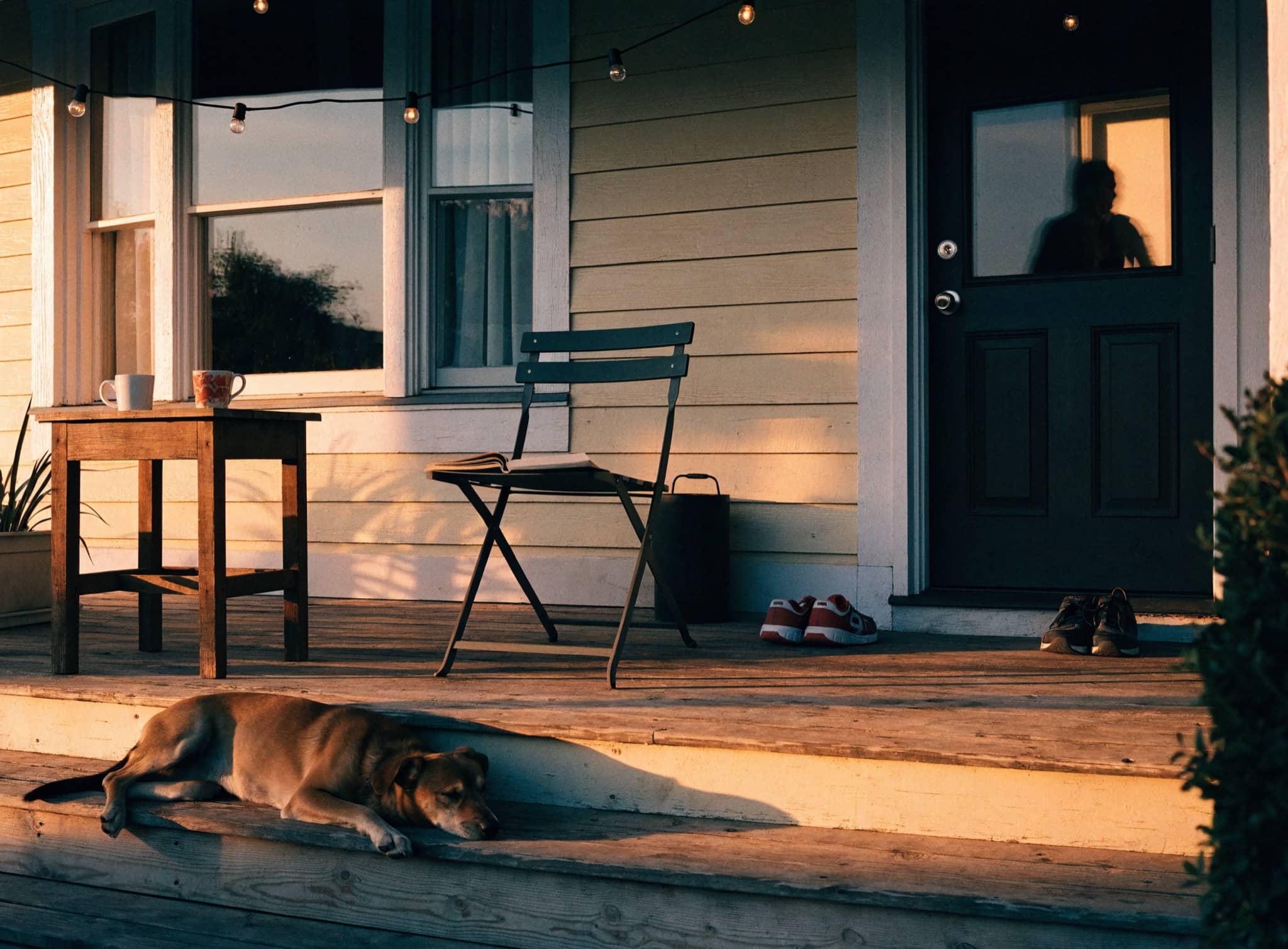 Traditional brick home with a deep front porch and rocking chairs in late afternoon light
